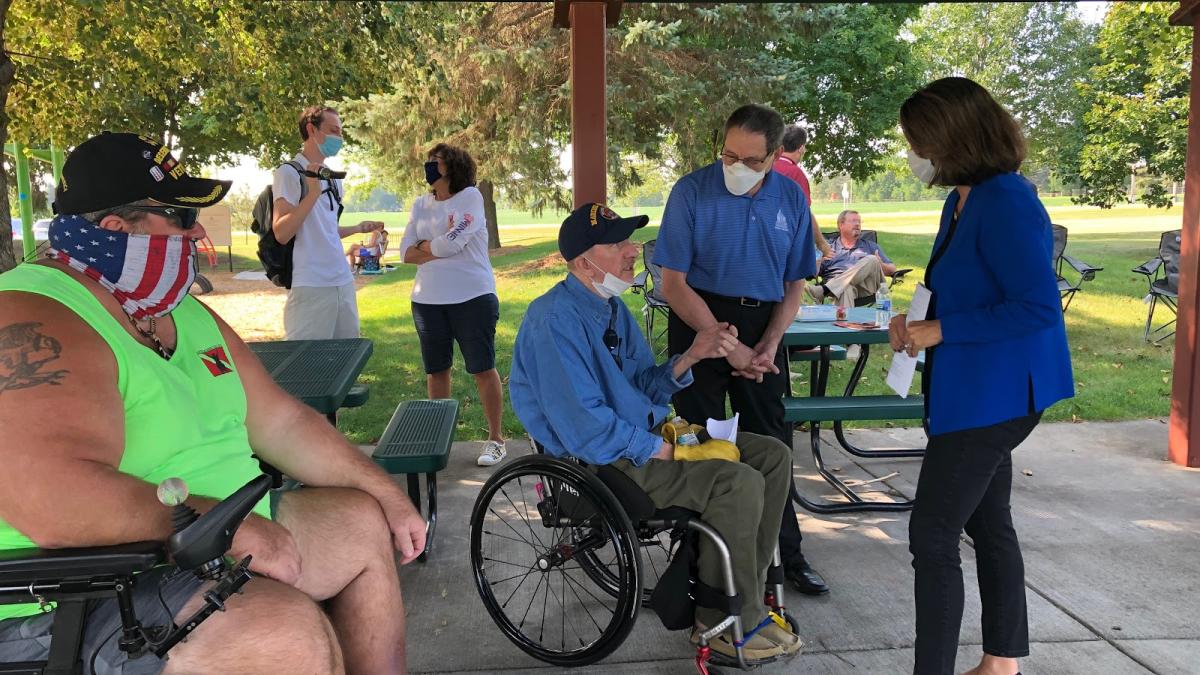 Rep. Angie Craig speaks with local veterans while visiting the future site of the Veterans Memorial Greenway